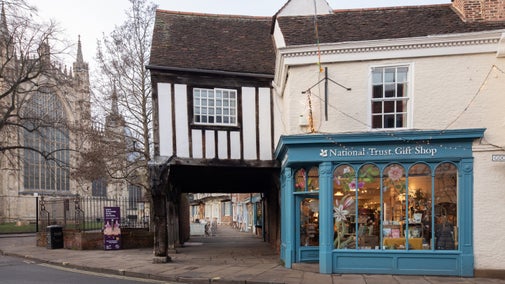 Exterior of a large shop saying National Trust with a large timber building and Minster